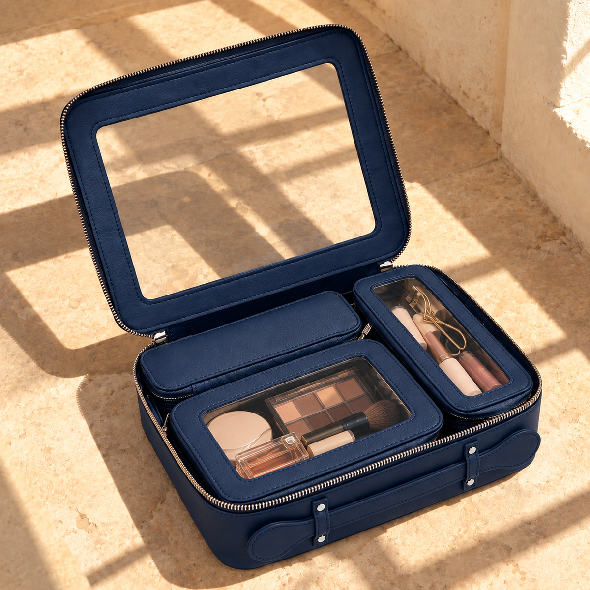 The 4-in-1 Case in Midnight Blue, open, with three inner pouches holding makeup